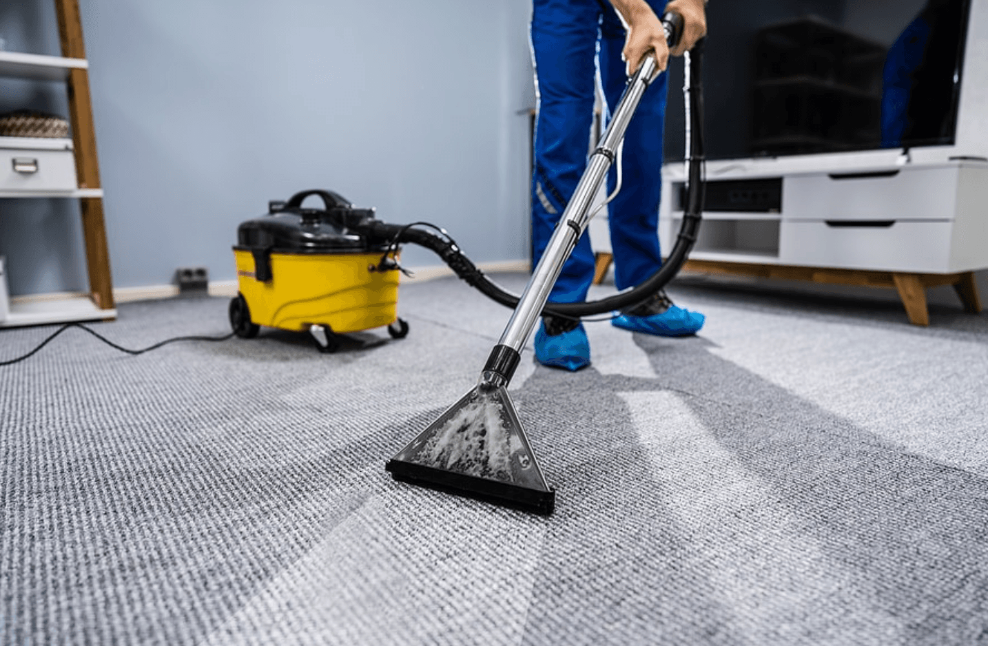 Technician steam cleaning a carpet with a professional extraction machine